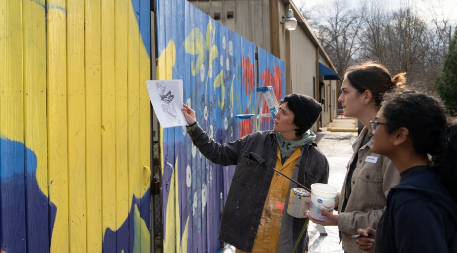 Caitlin La Dolce and student volunteers discussing the exterior mural design at Bigger Vision Athens.