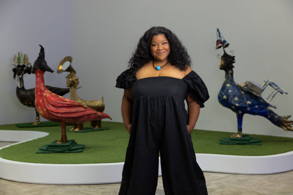 Portrait of vanessa german posing in front of artworks in her solo exhibition vanessa german: SAD RAPPER at Kasmin Gallery, New York, 2022.